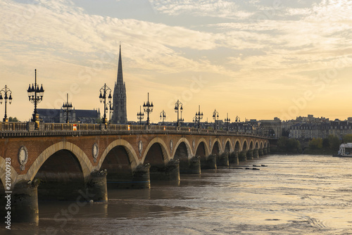 Pont de Pierre stone bridge on the river garonne in Bordeaux, France at sunset with the st michel church in the background © littlej78