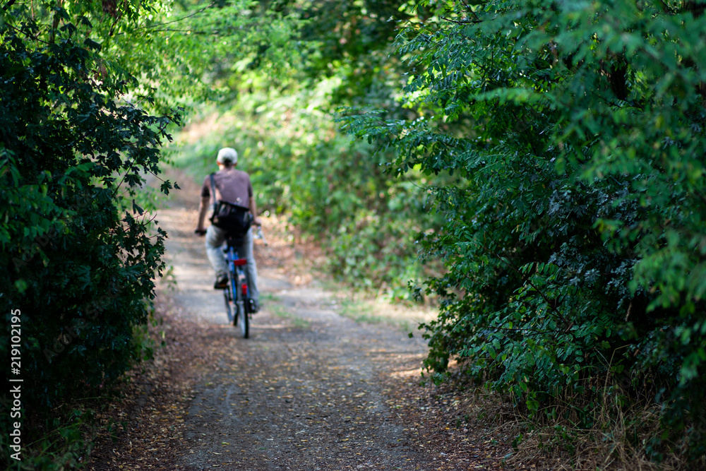 Blurred man cycling from work on a path in the forest in the middle of the city