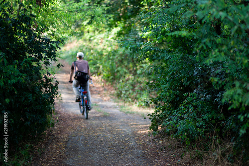 Blurred man cycling from work on a path in the forest in the middle of the city