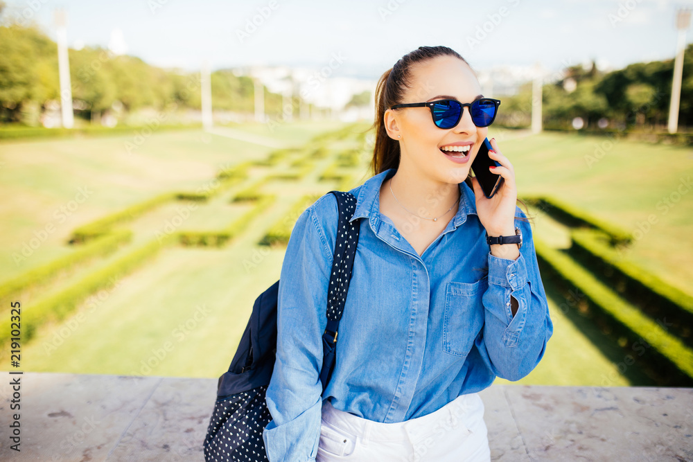 Young woman in sunglasses talking on a mobile against a plant background Young woman in sunglasses talking on a mobile against a plant background