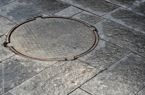 Metal menhole in the stone pavement