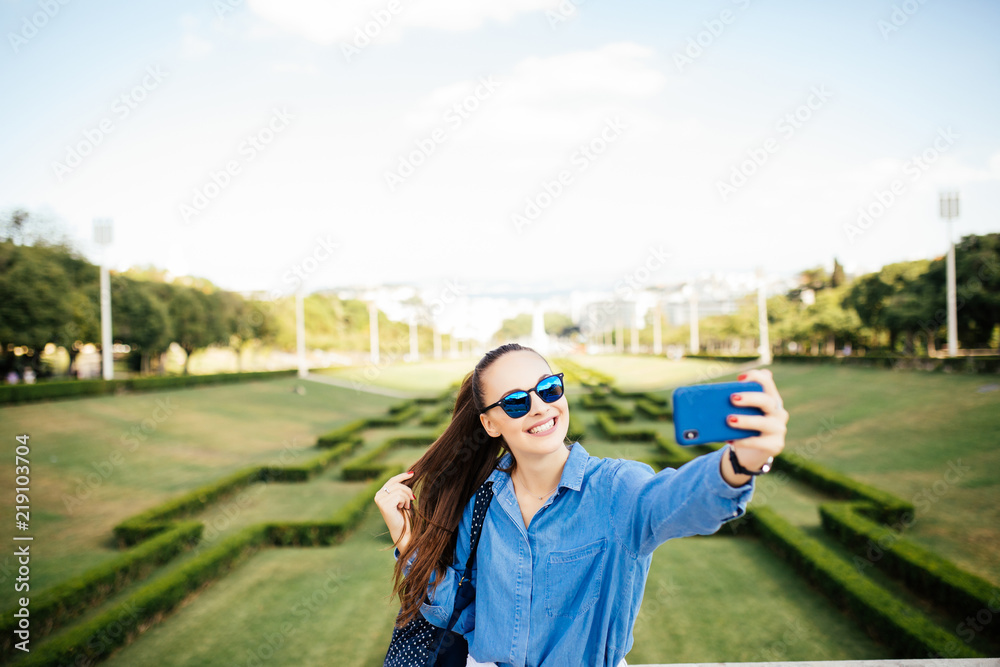 Young woman using mobile phone taking selfie in the park Young woman using mobile phone taking selfie in the park