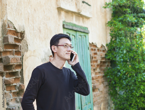 Asian man using smartphone outsite in old town. photo