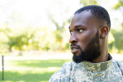 portrait of african american soldier in military uniform looking away in park