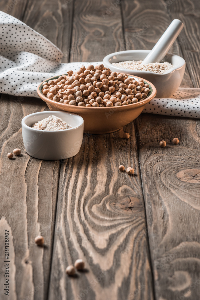 Close up view of raw chickpeas, spices and garlic (hummus ingredients) on wooden tabletop Close up view of raw chickpeas, spices and garlic (hummus ingredients) on wooden tabletop