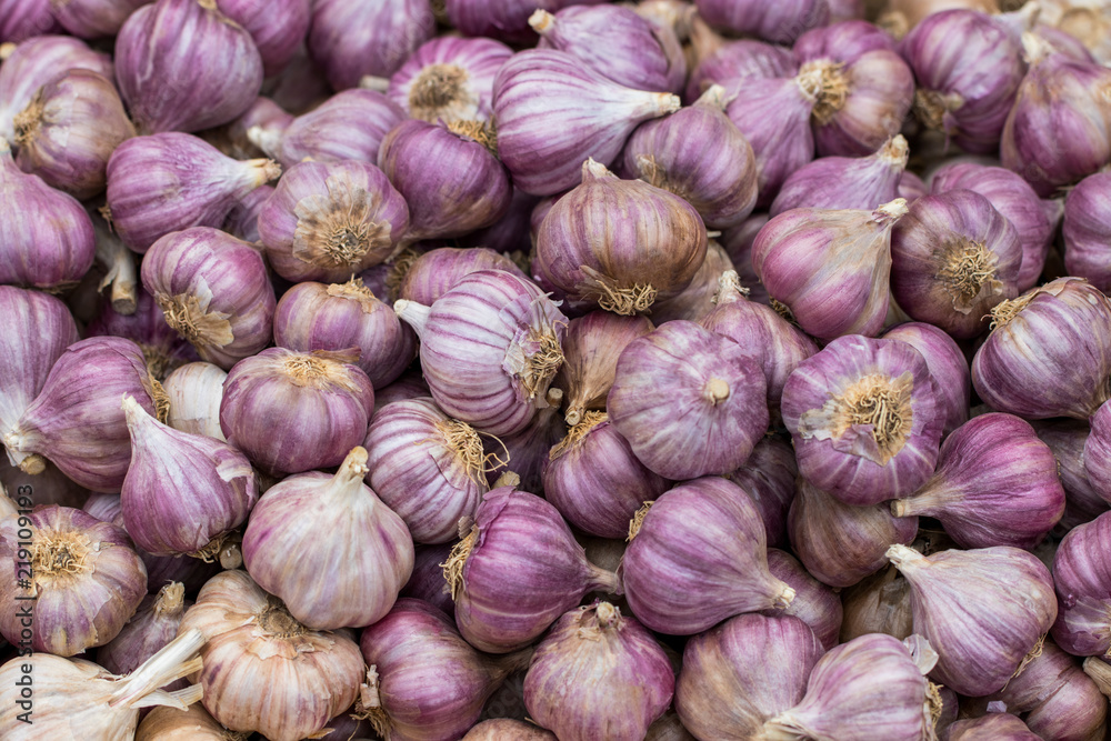 Garlic on the counter of the vegetable market. Close-up and top view of fresh vegetables on store shelves. Ingredients for salads and light snacks. Harvest from the farm. Soft focus Garlic on the counter of the vegetable market. Close-up and top view of fresh vegetables on store shelves. Ingredients for salads and light snacks. Harvest from the farm. Soft focus