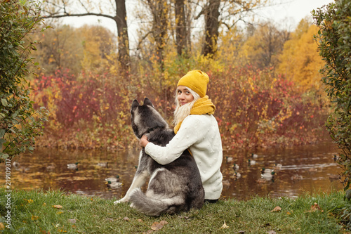 Young woman with her dog husky outdoors on autumn background