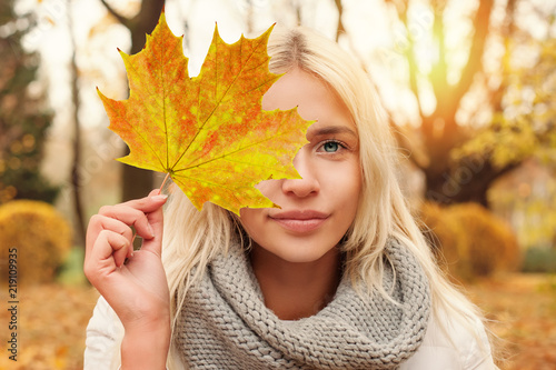 Young woman with fall leaf outdoors in autumn park