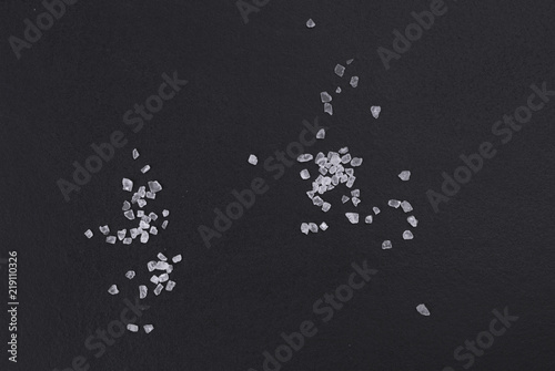 Schilderij op canvas Handful of sea salt scattered on a black background top view