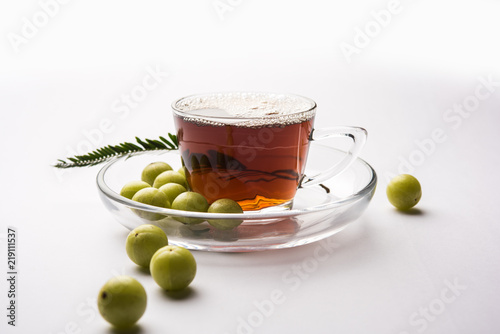 pouring amla Tea or Avla Chai in transparent glass cup with saucer over white or black background. Popular Ayurvedic medicine from India photo