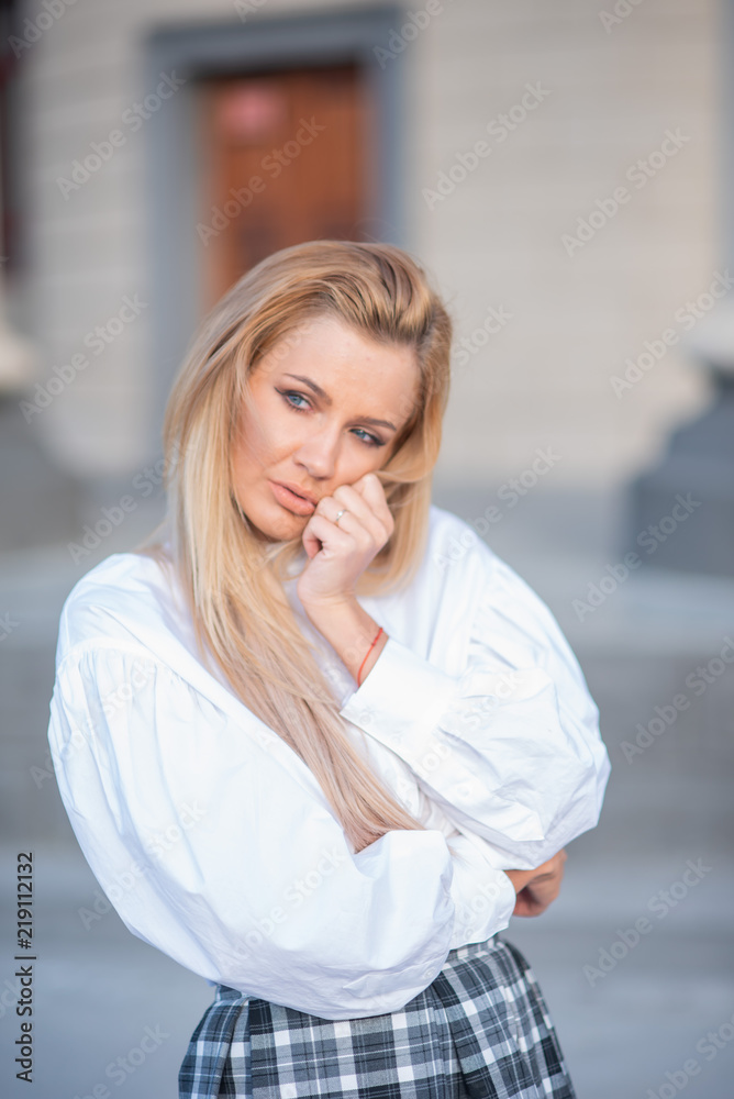 portrait of a blonde on a building background with columns. beautiful blonde in a white blouse smiling portrait of a blonde on a building background with columns. beautiful blonde in a white blouse smiling