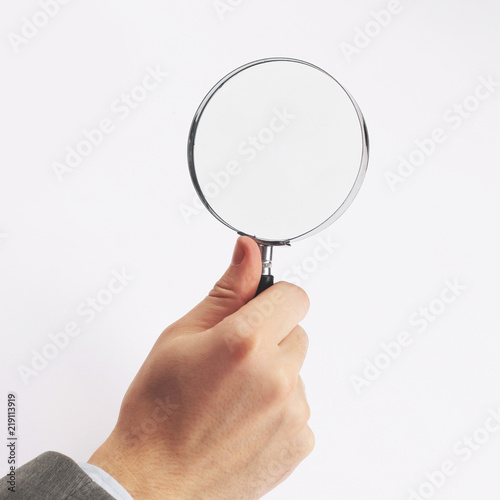 Man's hand, holding classic styled magnifying glass, closeup isolated on white background,