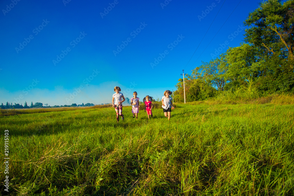 Large group of kids running in summer field with blue sky background Large group of kids running in summer field with blue sky background