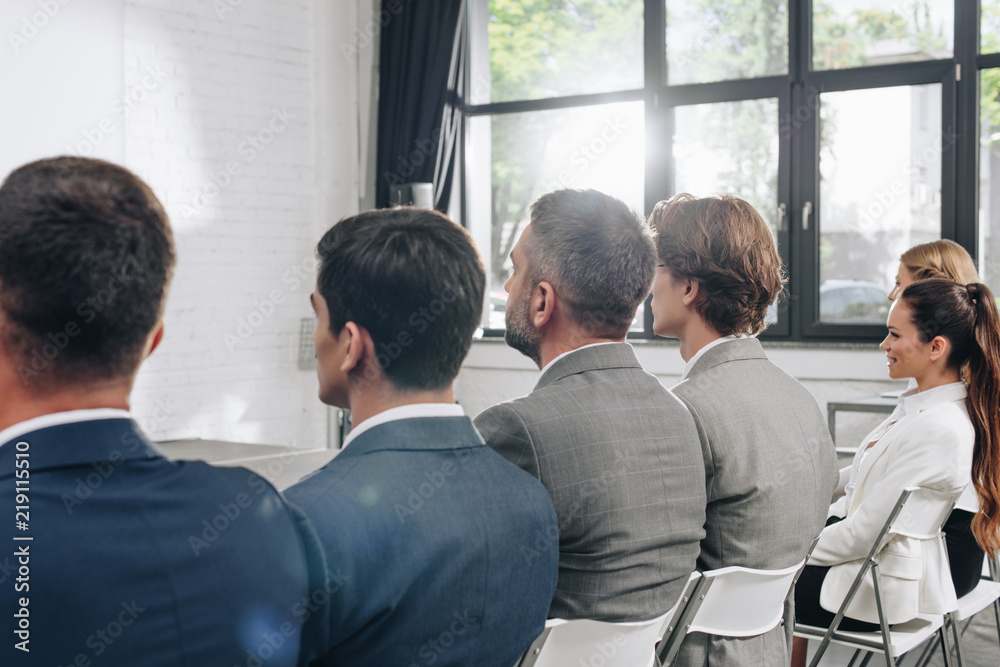 rear view of businesspeople sitting on chairs during training in hub rear view of businesspeople sitting on chairs during training in hub