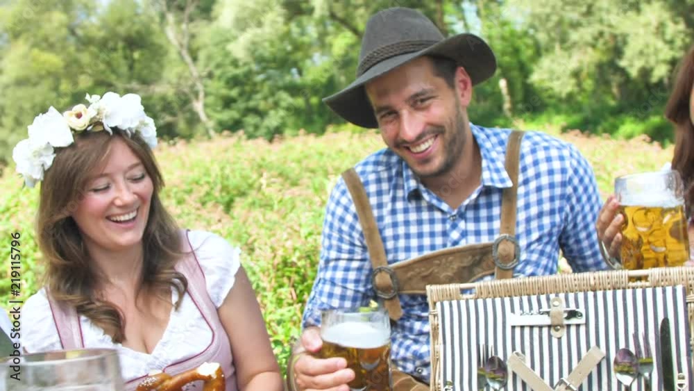 Oktoberfest Freunde in Lederhosen und Dirndl trinken Bier an der Isar