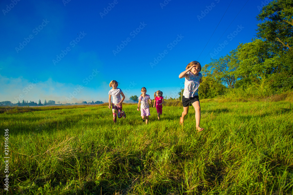 Large group of kids running in summer field with blue sky background