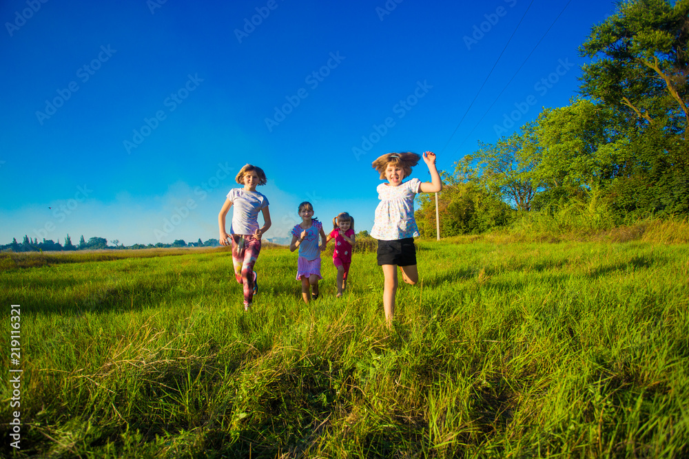 Large group of kids running in summer field with blue sky background Large group of kids running in summer field with blue sky background