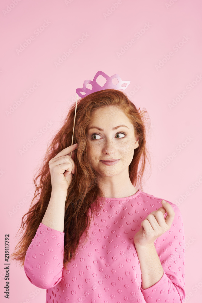 Portrait of interested woman with crown peeking at studio shot Portrait of interested woman with crown peeking at studio shot