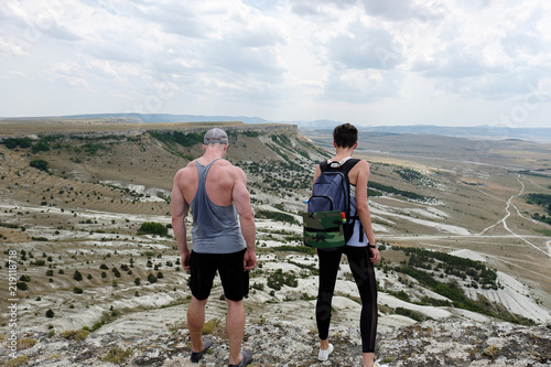 Muscular man and young woman hiker in mountains. Travel, vacation, trekking, hiking concept