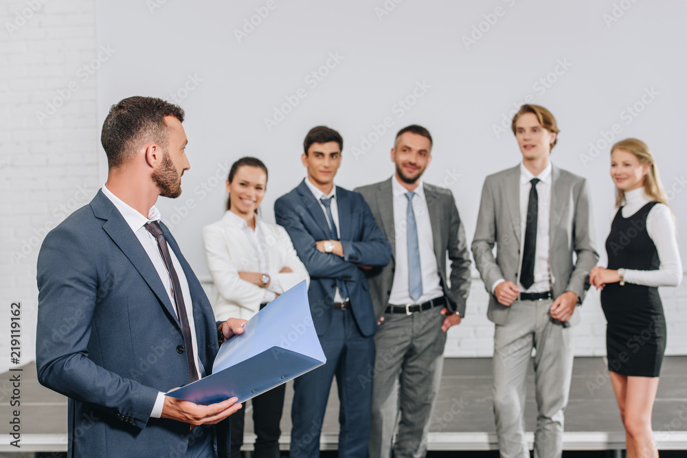 coach standing with clipboard near businesspeople in hub coach standing with clipboard near businesspeople in hub