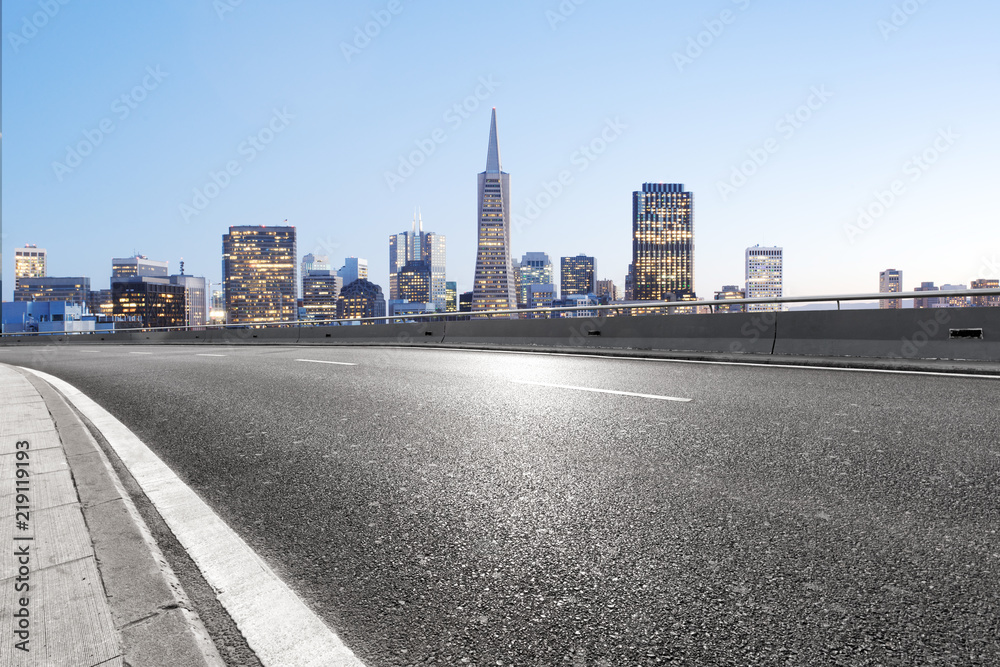 empty asphalt highway street with city skyline