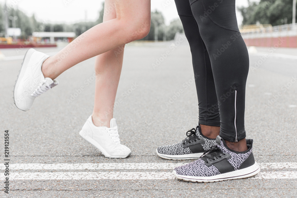 Love sport concept - running couple kissing. Closeup of running shoes and girl standing on toes to kiss boyfriend during jogging workout training outdoors Love sport concept - running couple kissing. Closeup of running shoes and girl standing on toes to kiss boyfriend during jogging workout training outdoors