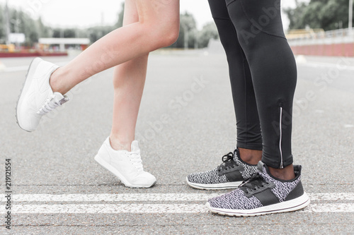 Love sport concept - running couple kissing. Closeup of running shoes and girl standing on toes to kiss boyfriend during jogging workout training outdoors