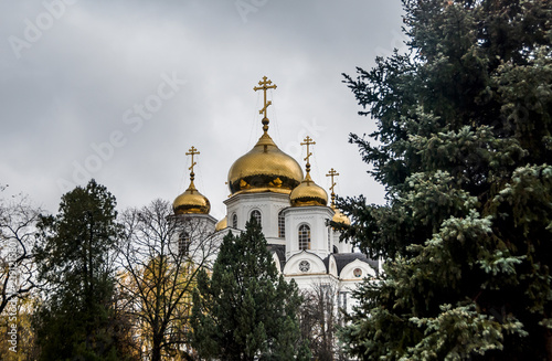 Golden domes of a temple with crosses against a cloudy autumn sky