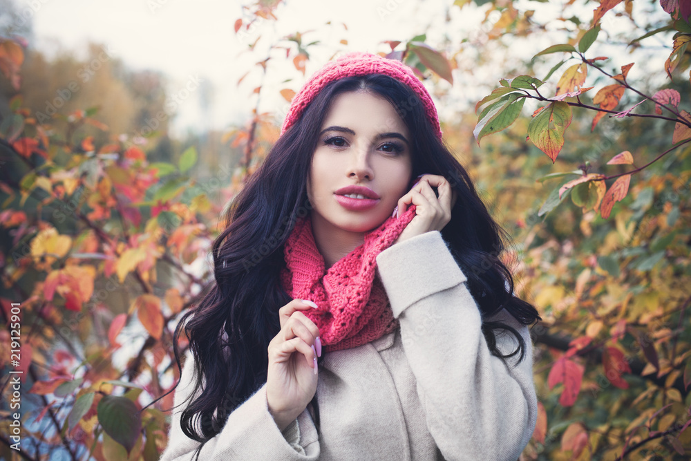 Beautiful autumn woman with long dark hair holding red maple leaf outdoors. Beautiful girl in fall park Beautiful autumn woman with long dark hair holding red maple leaf outdoors. Beautiful girl in fall park