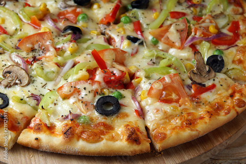 Bright pizza, cut into pieces, with vegetables and mushrooms