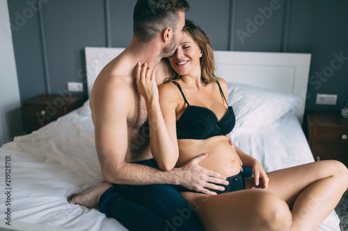Happy pregnant woman enjoying with husband in bedroom