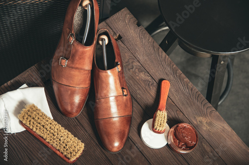 Monk shoes arranged on a wooden table with accessories for cleaning shoes