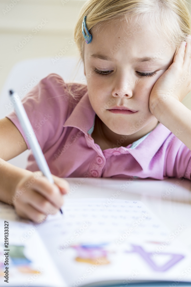 Portrait of bored little girl writing numbers in exercise book Portrait of bored little girl writing numbers in exercise book