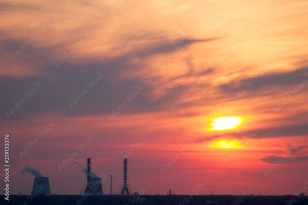 Sunset over the city. CHP pipes, power station. Industrial landscape. Bright sunset over the horizon