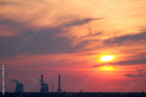 Sunset over the city. CHP pipes, power station. Industrial landscape. Bright sunset over the horizon