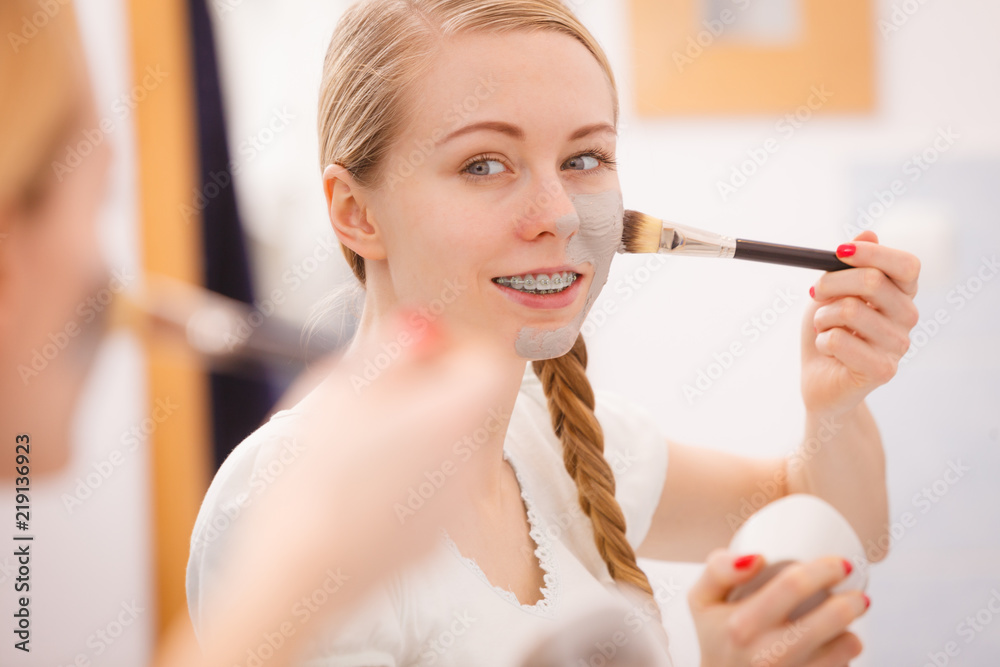 Woman applying with brush clay mud mask to her face Woman applying with brush clay mud mask to her face