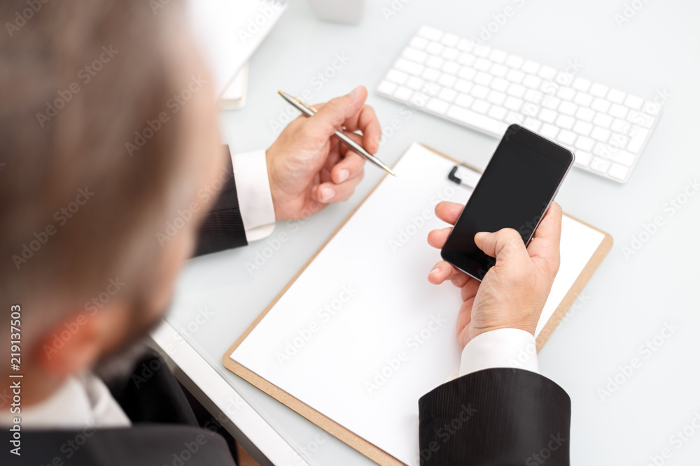 Male using modern smartphone and writing with pen business concept mockup Male using modern smartphone and writing with pen business concept mockup