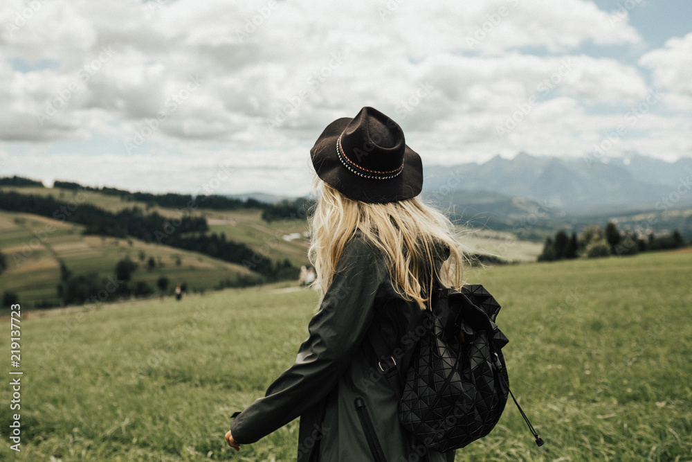 Beautiful hipster girl is hiking in the mountains. Hiking concept. Mountains landscape view