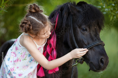 Cute little girl with black pony in the park