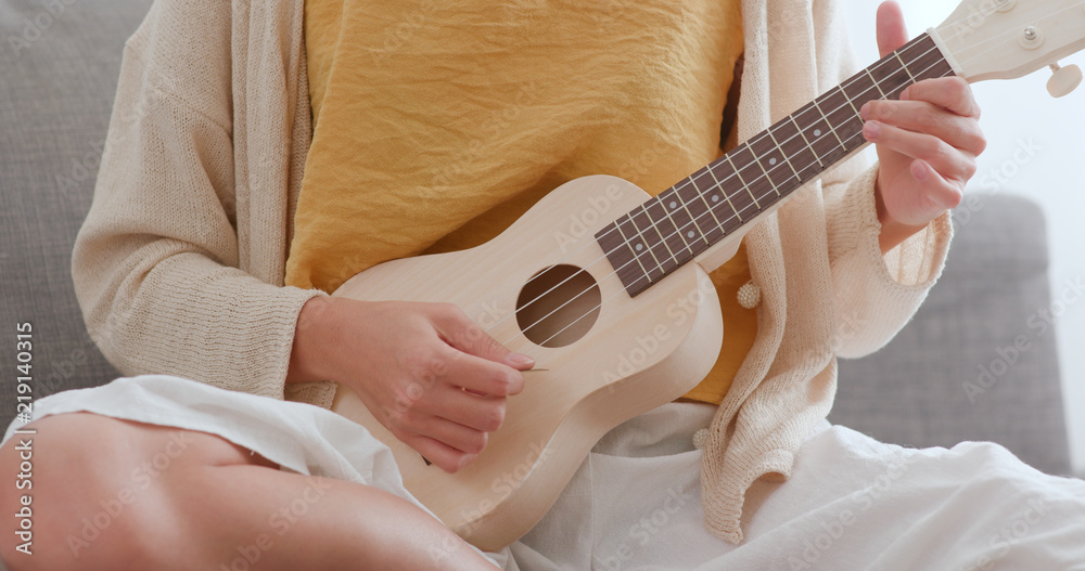 Fototapeta premium Woman playing song with ukulele at home