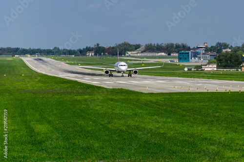 airplane on runway, green grass, blue sky