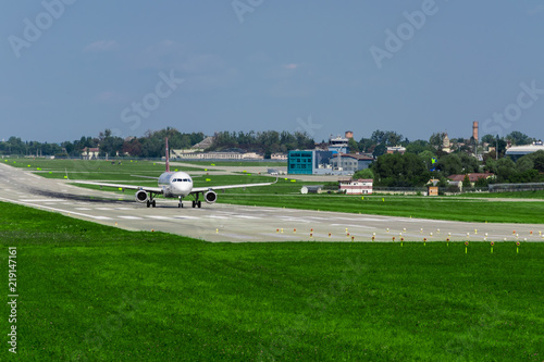 airplane on runway, green grass, blue sky