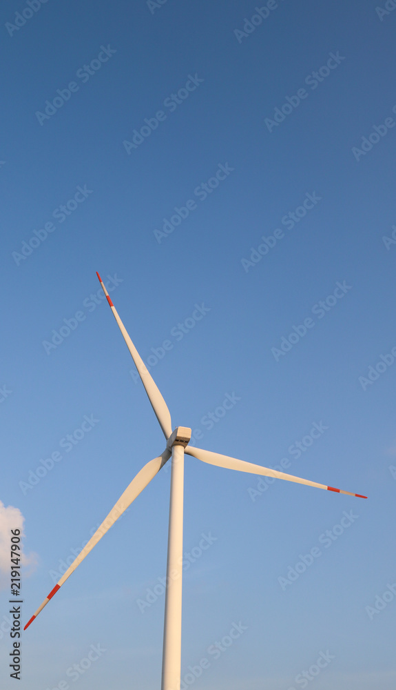 Vertical view of electric turbines with blue sky background.