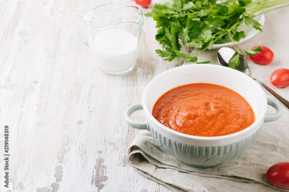 Bowl of homemade tomato soup with cream and parsley on wooden table. Copy spase for your text Bowl of homemade tomato soup with cream and parsley on wooden table. Copy spase for your text