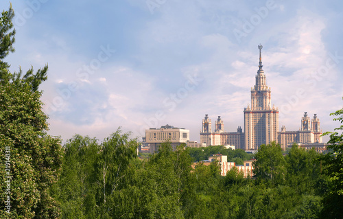 Moscow State University (MSU) in beautiful view of the main skyscraper-building from the park with green trees and expressive clouds