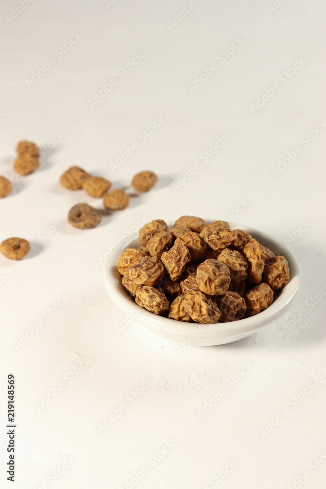 Tigernuts / earth almonds / nutsedges in a small bowl, on white surface, copy space Tigernuts / earth almonds / nutsedges in a small bowl, on white surface, copy space