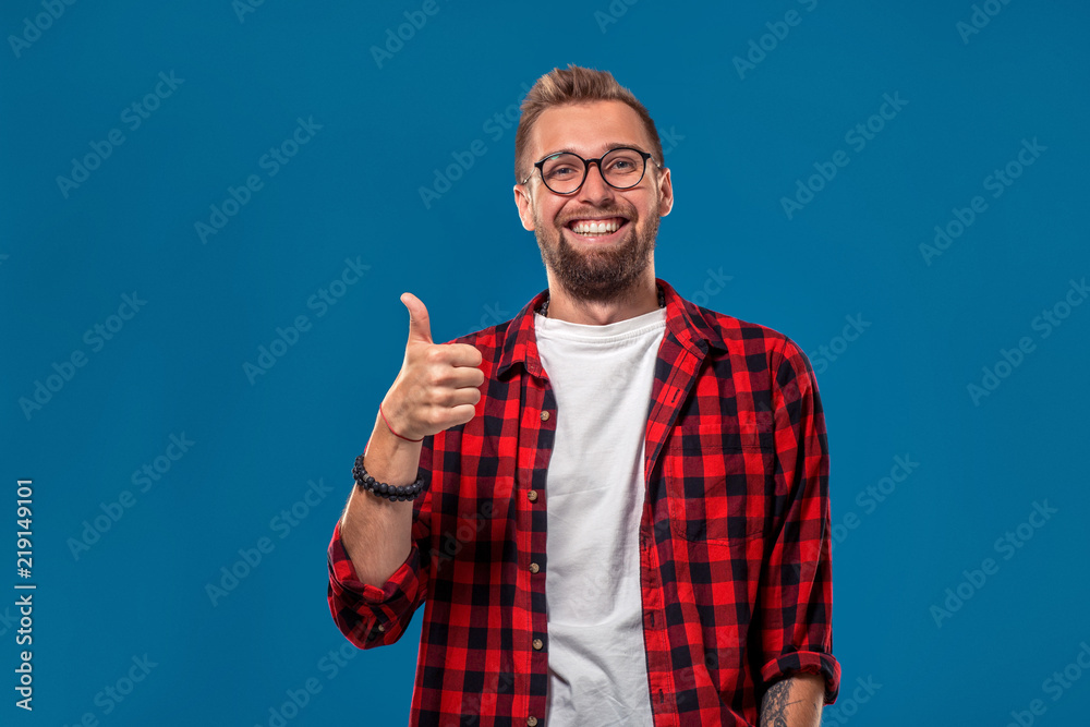 Naklejka premium Emotional and people concept: young bearded man in checkered shirt. Hipster style. The guy shows his hand - It's okay