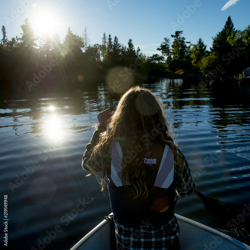 Girl on boat in a lake at morning sunlight, Lake of The Woods, Kenora, Lake of The Woods, Ontario, Canada photo