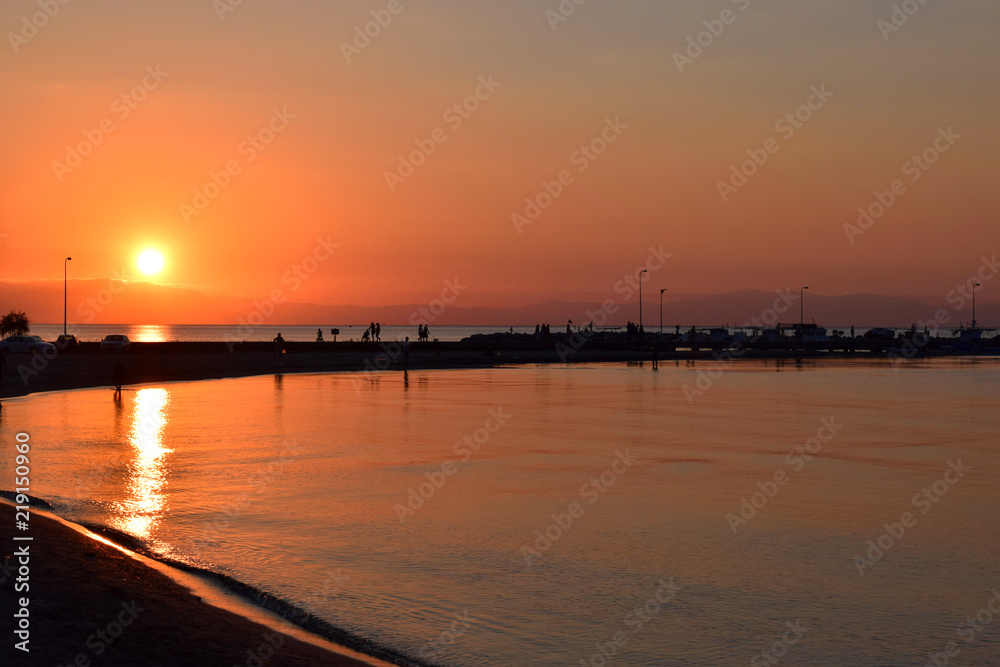 Beautiful sunset in Peraia, Thessaloniki Greece. Silhouettes walking on the shore