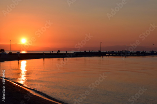 Beautiful sunset in Peraia  Thessaloniki Greece. Silhouettes walking on the shore